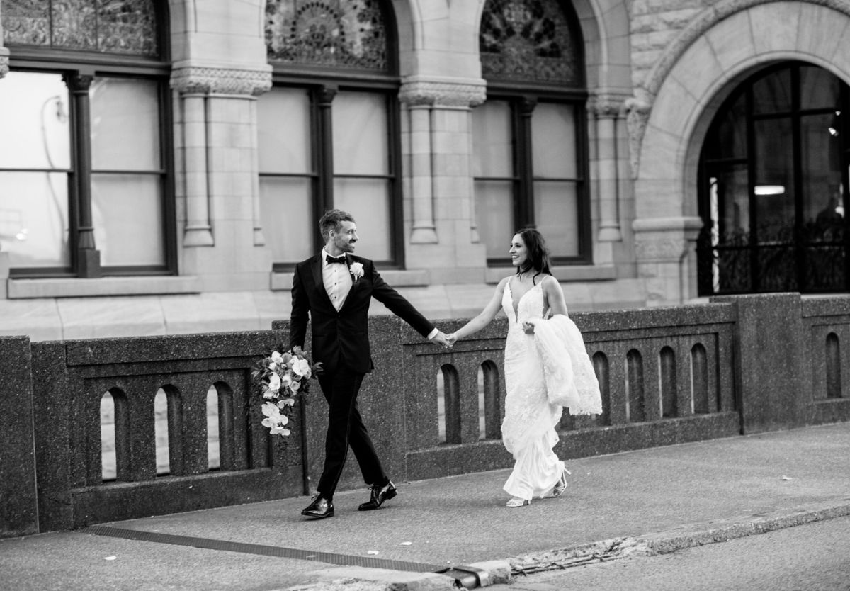 Bride and groom walking outside historic building