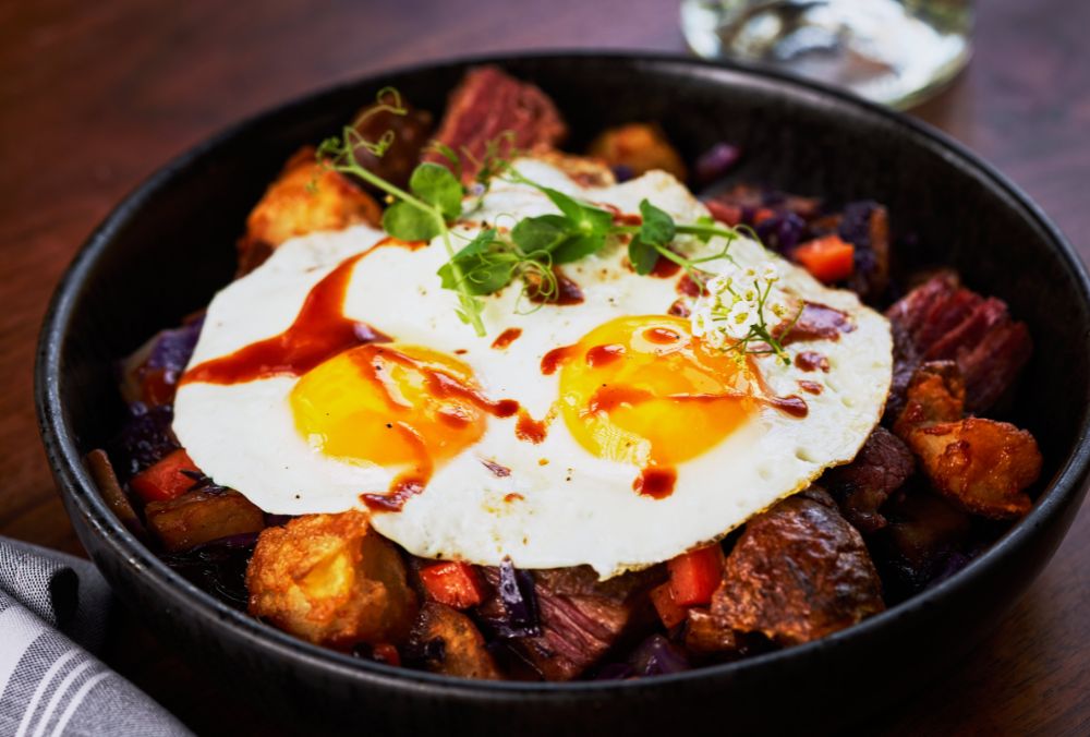 A hearty dish with two sunny-side-up eggs on top of a bed of roasted potatoes